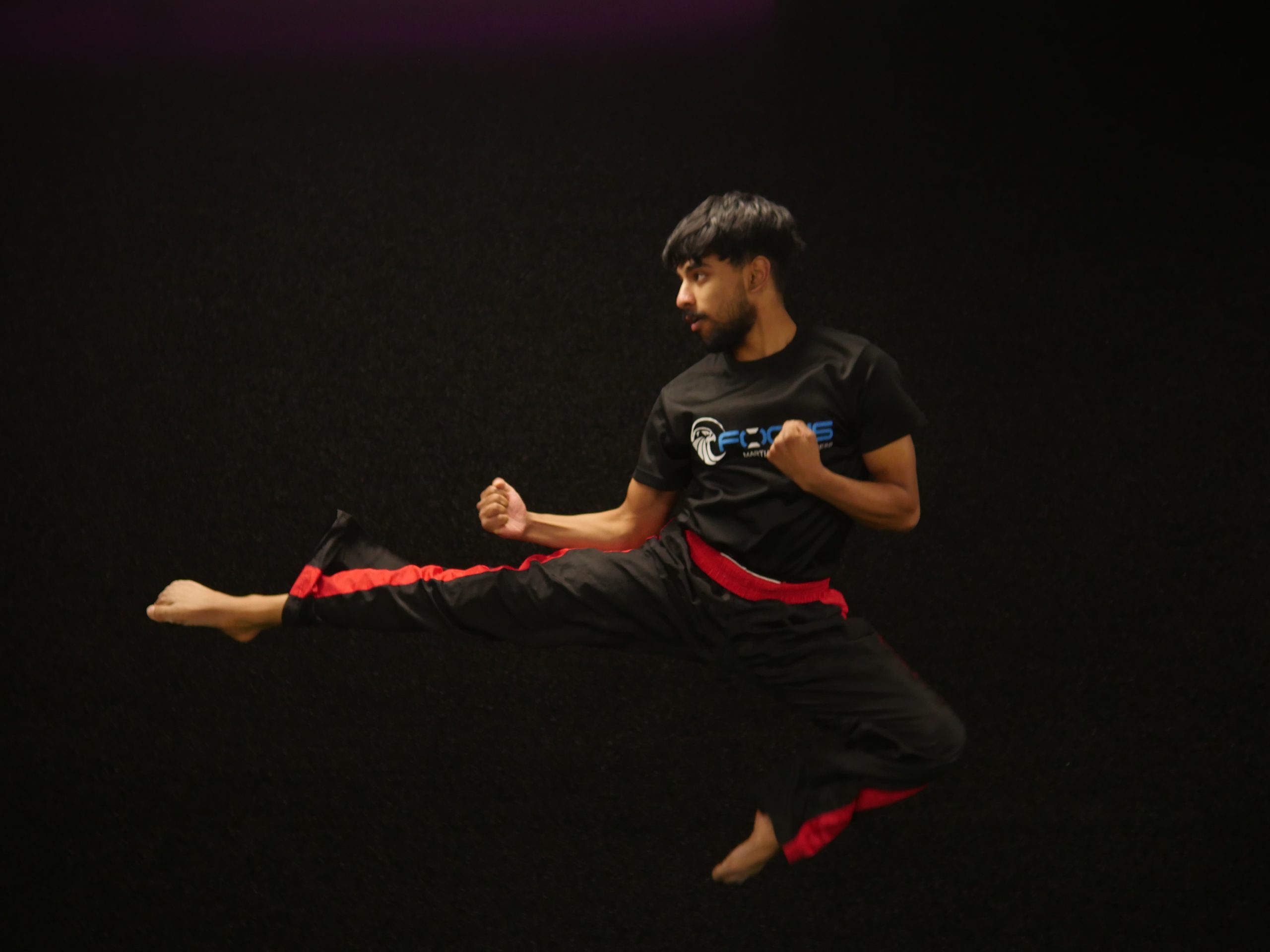 A Focus Fitness martial artist performing a flying kick