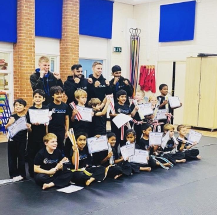 A grading day group photo with students holding their new belts and certificates